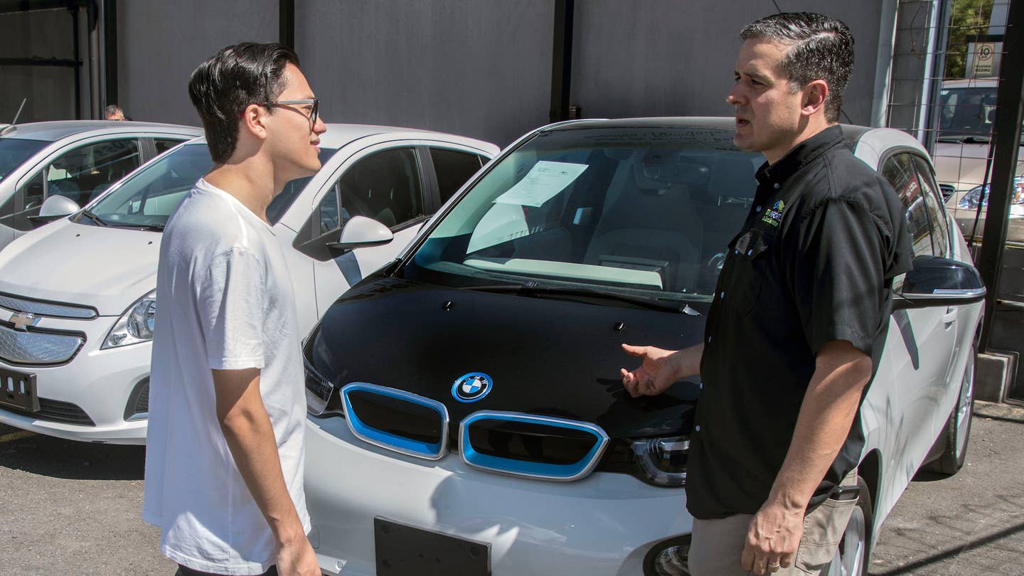 Mariano Avalos (R), owner of a car dealer that sells used electric cars imported from the United States, talks to a customer in San Jose on December 13, 2018. - Electric vehicles slowly gain space in Costa Rica's congested streets, a country that prides itself on being an ecological paradise and works on an agenda to decarbonize its economy. Despite the 600 electric cars in private hands seem like a drop of water in a vehicle fleet of around 1.4 million, experts foresee an exponential growth. (Photo by Ezequiel BECERRA / AFP) (Photo credit should read EZEQUIEL BECERRA/AFP via Getty Images)